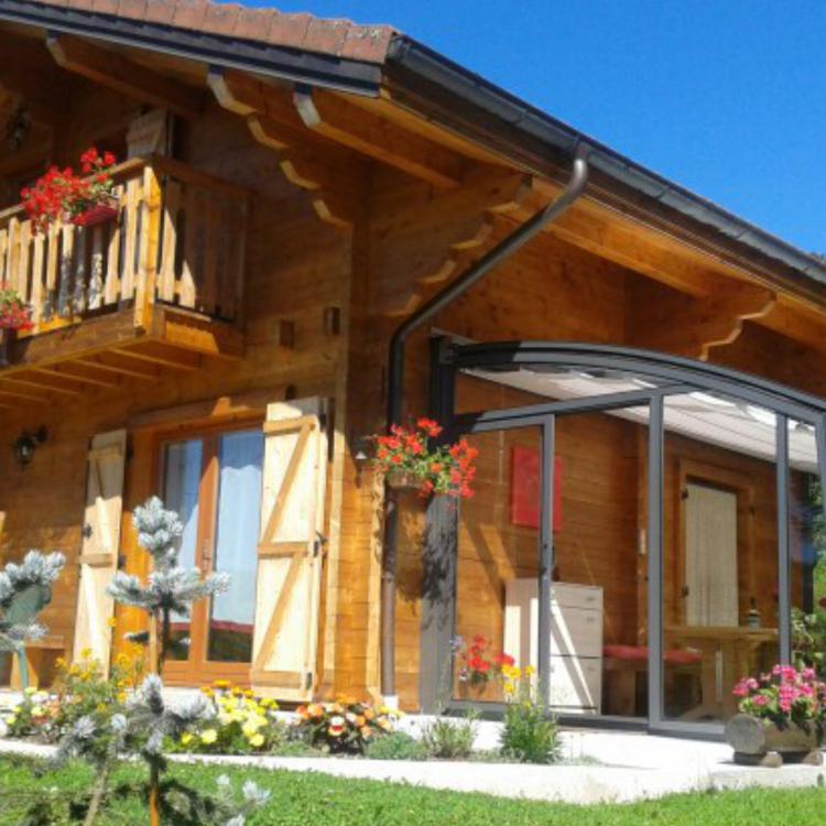 Abri terrasse angulaire et rétractable contre un chalet en montagne